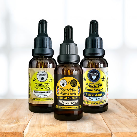 Three bottles of Nickle City Beards Blend beard oil on a wooden surface with a white background.