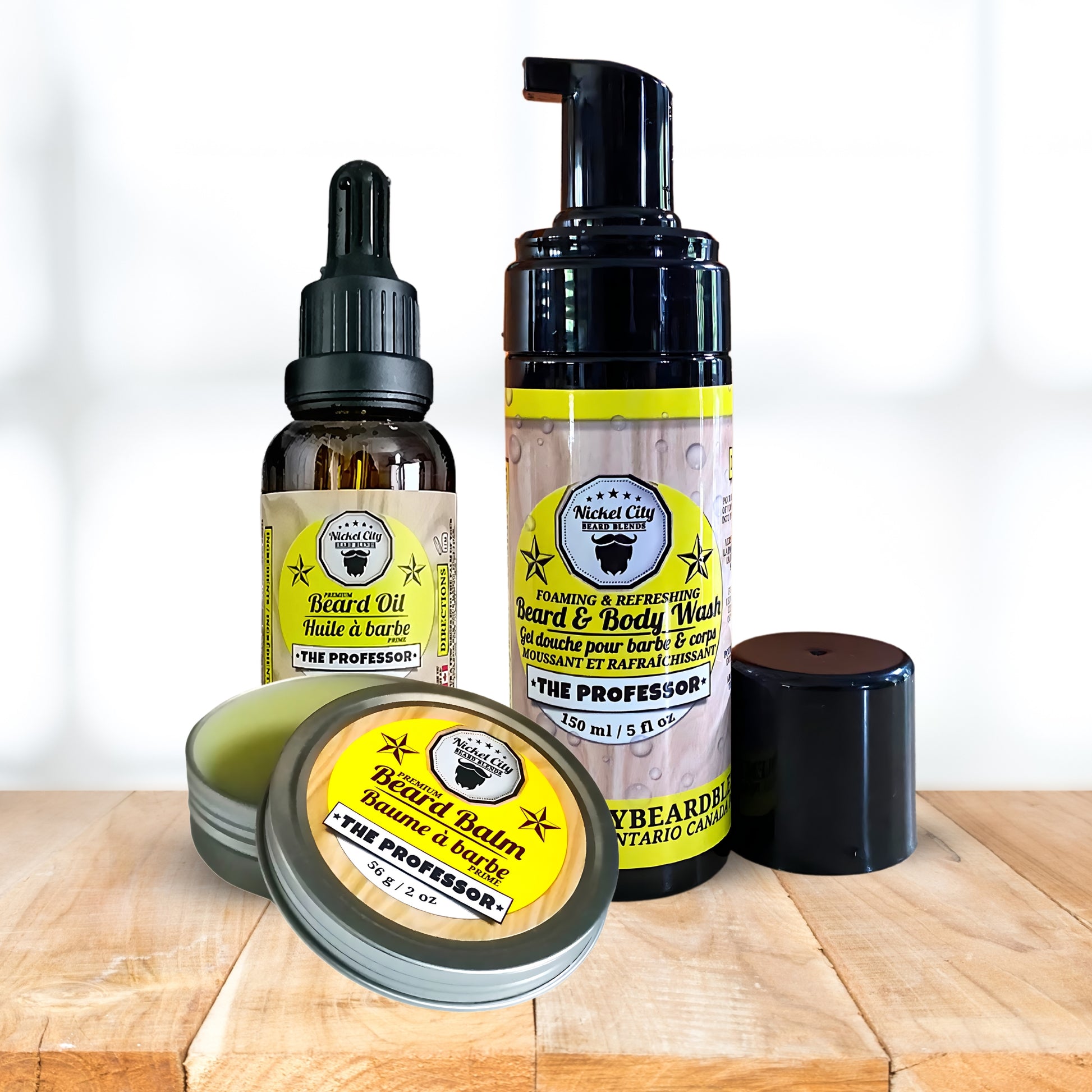 Set of beard care products including oil, balm, and wash on a wooden surface with a white background.