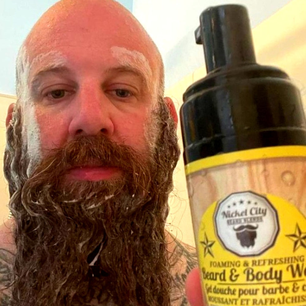 Man with beard in shower holding beard wash bottle 