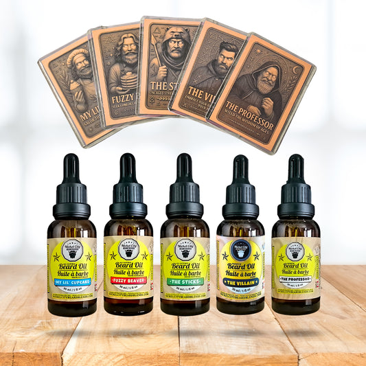 Five bottles of beard oil with labels and five playing card-sized product cards on a wooden surface.