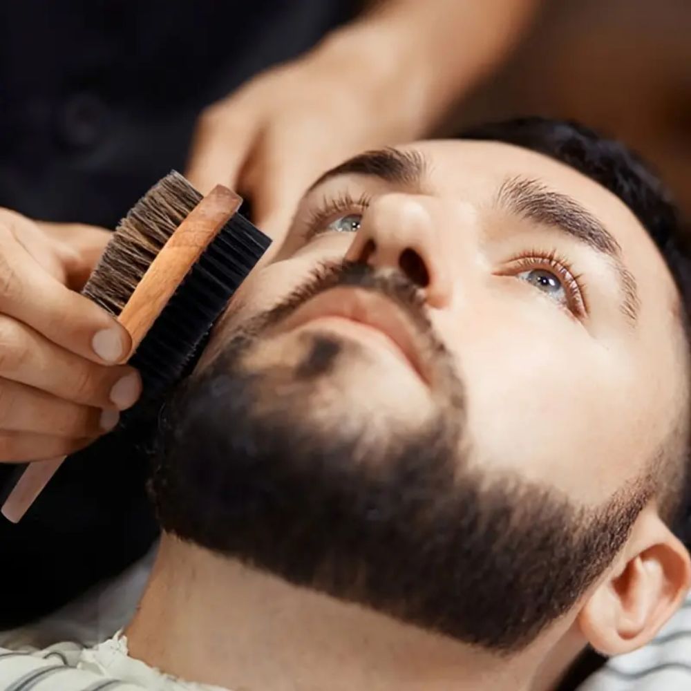 Barber brushing a man's beard with a wooden beard brush