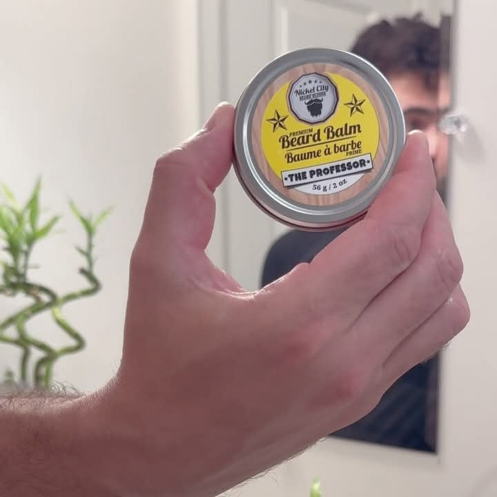 Hand holding The Professor beard balm tin